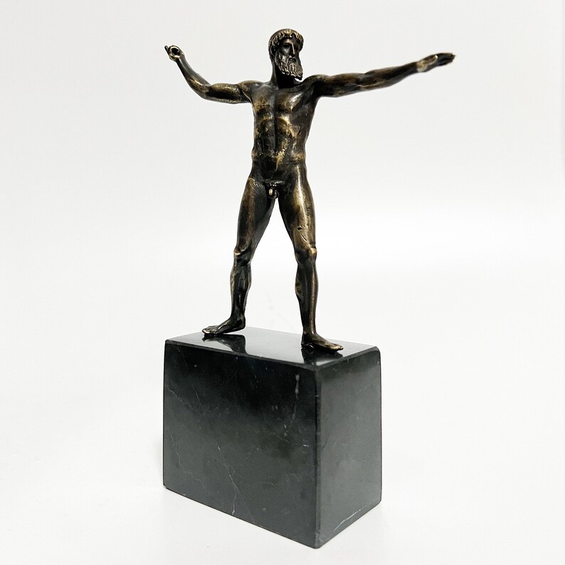 May include: Bronze sculpture of a nude male figure standing on a black marble base. The figure has a beard and is posed with arms outstretched.