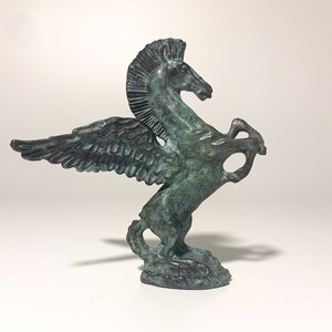 May include: A green bronze statue of a winged horse, also known as a Pegasus, with its wings spread out. The horse is rearing up on its hind legs, with its head turned to the side.