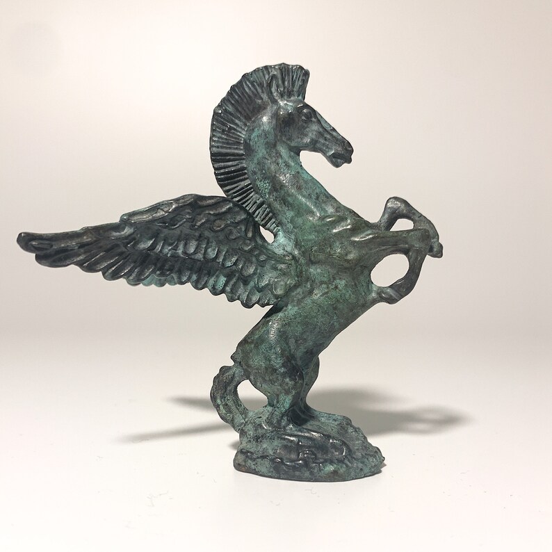 May include: A green bronze statue of a winged horse, also known as a Pegasus, with its wings spread out. The horse is rearing up on its hind legs, with its head turned to the side.