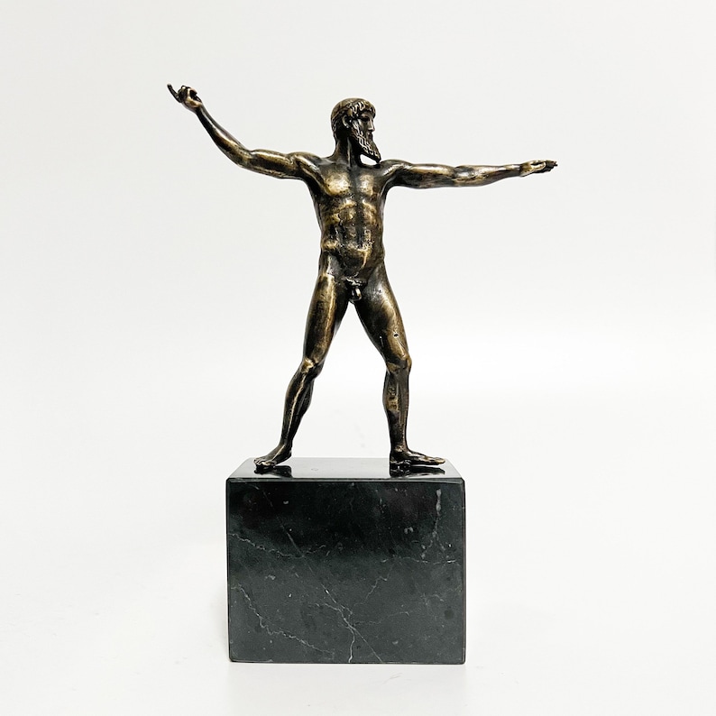 May include: Bronze sculpture of a nude male figure standing with arms outstretched on a black marble base.