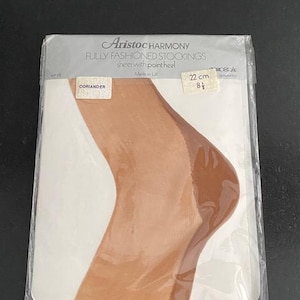 May include: Aristoc Harmony fully fashioned stockings in coriander colour, packaged in clear plastic. The label displays the text Aristoc Harmony, Fully Fashioned Stockings, sheer with point heel, Made in UK, and a size tag of 22 cm or 8.5 inches.
