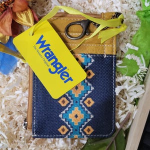 May include: A small, mustard yellow leather wallet with a zipper closure and a key ring. The wallet has a blue and orange geometric pattern on the front and a yellow tag that says "Wrangler The Western Original".