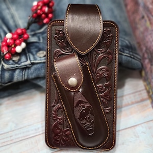 May include: A brown leather phone case with a floral design and a separate pocket for a knife. The case has a yellow stitching detail.