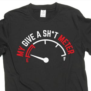 Könnte beinhalten: Schwarzes T-Shirt mit einer Messgerätegrafik. Die Anzeige lautet "My Give A Sh*t Meter" in weißem und rotem Text. Die Nadel zeigt auf die leere Seite der Anzeige.
