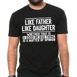 May include: Black t-shirt with white text that reads "Like father like daughter whether that is a good or bad thing is a matter of opinion."