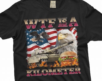 May include: Black t-shirt with a graphic design featuring an American flag, an eagle, a tank, and a hamburger. The text "WTF IS A KILOMETER" is printed on the shirt.