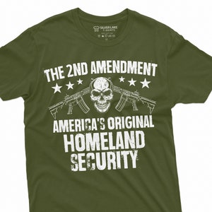 May include: A green t-shirt with a white graphic print that says "The 2nd Amendment America's Original Homeland Security". The graphic also includes a skull and crossbones with two rifles.