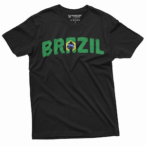 Puede incluir: Camiseta negra con un gr&aacute;fico desgastado de "BRASIL" en verde y amarillo con la bandera brasile&ntilde;a. El gr&aacute;fico est&aacute; centrado en la camiseta.