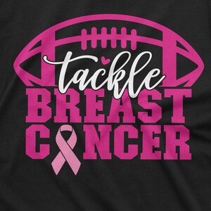May include: Pink and white graphic on a black t-shirt with a football and the text "Tackle Breast Cancer".