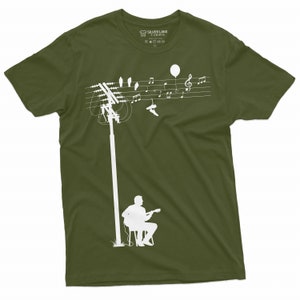 K&ouml;nnte beinhalten: Ein gr&uuml;nes T-Shirt mit einer wei&szlig;en Silhouette einer Person, die Gitarre spielt, unter einer Stromleitung mit Noten und V&ouml;geln. Das Etikett lautet "Silver Lake T-Shirts".