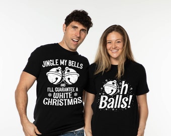 May include: Two people wearing black t-shirts with festive text and graphics. One shirt says "Jingle My Bells" with bell graphics, the other says "Oh Balls!" with a bell graphic and snowflakes. The shirts are on a white background.