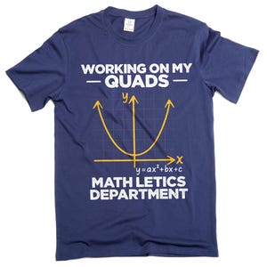 May include: Navy blue t-shirt with white text that reads "WORKING ON MY -QUADS-" and "MATH LETICS DEPARTMENT." A yellow parabola graph is centered below the text. The equation "y=ax²+bx+c" is below the graph.