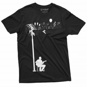 K&ouml;nnte beinhalten: Schwarzes T-Shirt mit einer wei&szlig;en Silhouette einer Person, die Gitarre spielt unter einer Stromleitung mit V&ouml;geln und Noten. Das Etikett lautet "Silver Lake T-shirts".