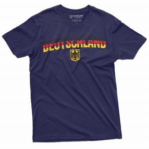 May include: A navy blue t-shirt with a distressed German flag design and the word "DEUTSCHLAND" printed in yellow, red, and black. The German eagle crest is centered below the text.