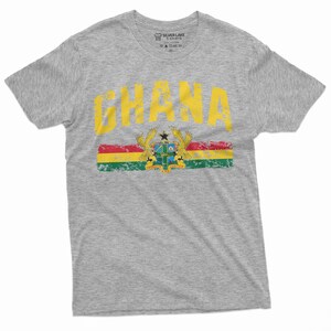May include: Gray t-shirt with a yellow distressed graphic of the word "GHANA" and the Ghanaian flag with the coat of arms.