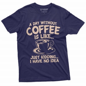 May include: A navy blue t-shirt with a distressed white graphic that reads "A day without coffee is like... Just kidding... I have no idea". The graphic also includes a stylized image of a coffee cup.