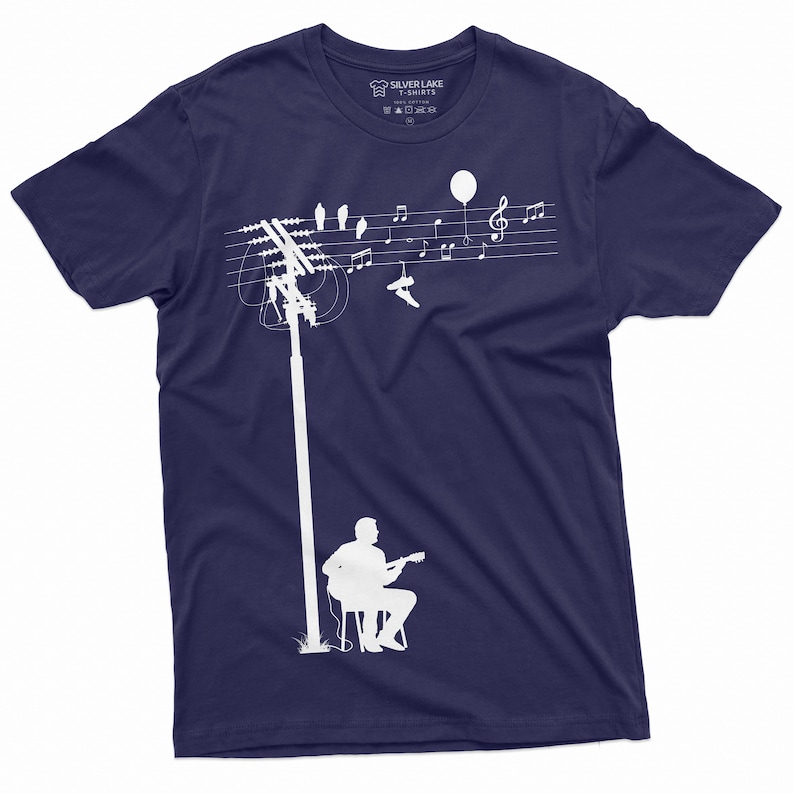 K&ouml;nnte beinhalten: Ein marineblaues T-Shirt mit einer wei&szlig;en Silhouette eines Mannes, der Gitarre spielt, unter einer Stromleitung mit V&ouml;geln und Noten. Das Etikett lautet "Silver Lake T-Shirts".