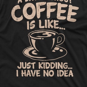 May include: A black t-shirt with a distressed white graphic that reads "A day without coffee is like..." and features a coffee cup and saucer. The text continues with "Just kidding... I have no idea."
