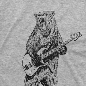 K&ouml;nnte beinhalten: Eine Schwarzwei&szlig;illustration eines B&auml;ren, der Bass spielt. Der B&auml;r br&uuml;llt und tr&auml;gt eine Kette um den Hals. Der Bass hat einen schwarzen Korpus und ein wei&szlig;es Schlagbrett.