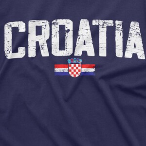 以下が含まれることがあります： 紺色のTシャツに、白で「CROATIA」という文字がかすれた感じでプリントされています。文字の下には、小さなクロアチアの旗がプリントされています。