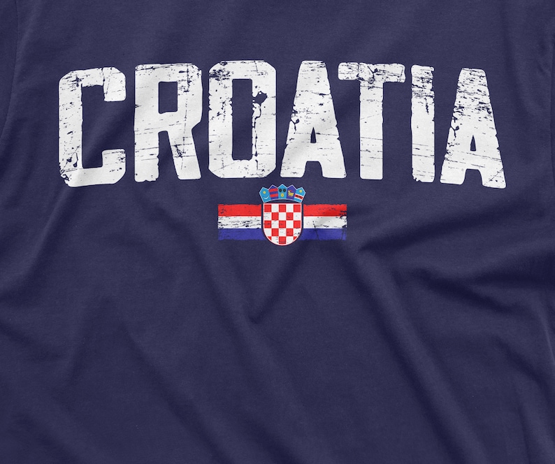 以下が含まれることがあります： 紺色のTシャツに、白で「CROATIA」という文字がかすれた感じでプリントされています。文字の下には、小さなクロアチアの旗がプリントされています。