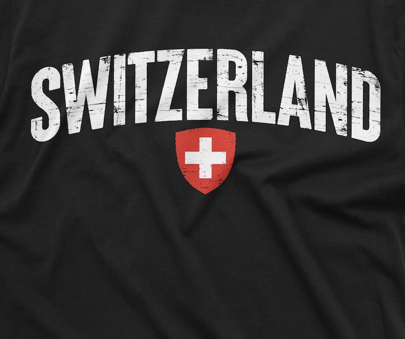 May include: Black t-shirt with white distressed text that reads "SWITZERLAND" and a red Swiss flag with a white cross in the centre.
