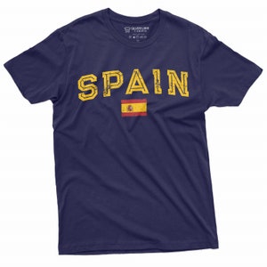 K&ouml;nnte beinhalten: Ein marineblaues T-Shirt mit dem Wort "SPAIN" in gelben Buchstaben mit einem Used-Look. Die spanische Flagge ist unter dem Wort gedruckt.