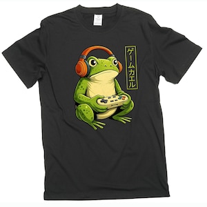 May include: Black t-shirt featuring a cartoon frog wearing orange headphones and holding a video game controller. The frog is green with yellow accents. Japanese text in a yellow rectangle is on the right side of the frog.