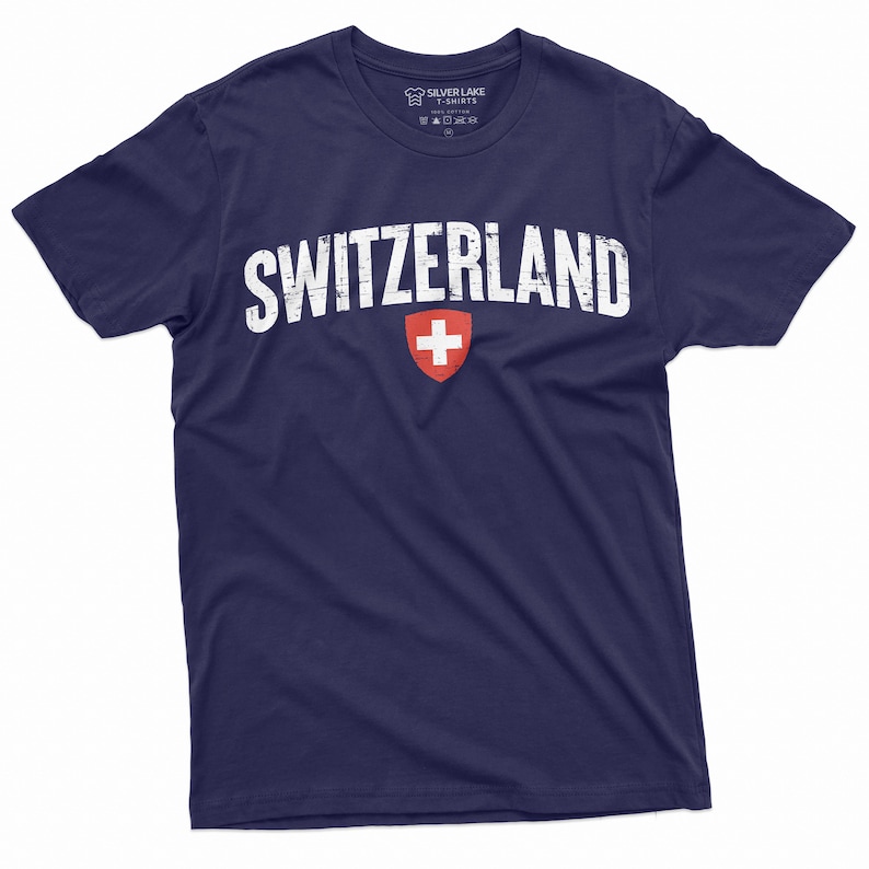 May include: A navy blue t-shirt with a white distressed graphic of the word "SWITZERLAND" and the Swiss flag.