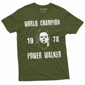 May include: A green t-shirt with a white graphic of a horror movie character's mask. The text "WORLD CHAMPION 19 78 POWER WALKER" is printed on the shirt.