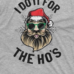 May include: A gray t-shirt with a graphic of Santa Claus wearing sunglasses and a beard. The text "I do it for the ho's" is printed on the shirt.