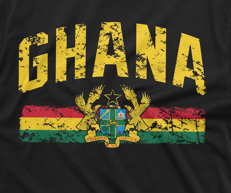 May include: A black t-shirt with a yellow distressed graphic of the word "GHANA" and a red, yellow, green, and black flag with a coat of arms featuring a star, eagle, and the words "Freedom and Justice".