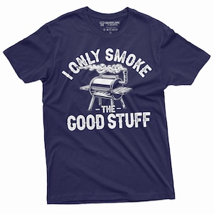 Puede incluir: Camiseta azul marino con un gráfico blanco de una parrilla con humo saliendo de ella. El texto "I only smoke the good stuff" está impreso en la camiseta.