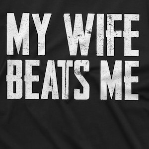 May include: Black t-shirt with white text that reads "My wife beats me".