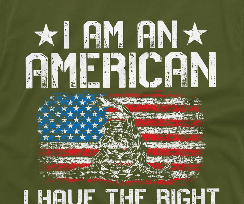 Puede incluir: Una camiseta verde con un gr&aacute;fico blanco desgastado de una bandera estadounidense con una serpiente y el texto "I am an American I have the right to bear arms".