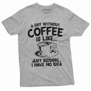 May include: A gray t-shirt with a black graphic that reads "A day without coffee is like... Just kidding... I have no idea". The graphic also includes a stylized image of a coffee cup and saucer.