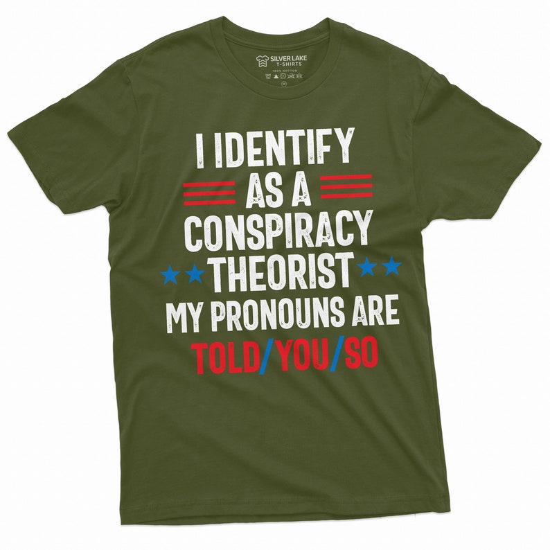 May include: A green t-shirt with the text "I identify as a conspiracy theorist. My pronouns are told/you/so" in white, red, and blue lettering. The text is in a distressed font style.