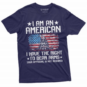 Puede incluir: Camiseta azul marino con un dise&ntilde;o de bandera estadounidense desgastado y el texto "Soy un estadounidense. Tengo derecho a portar armas. Tu aprobaci&oacute;n no es necesaria."
