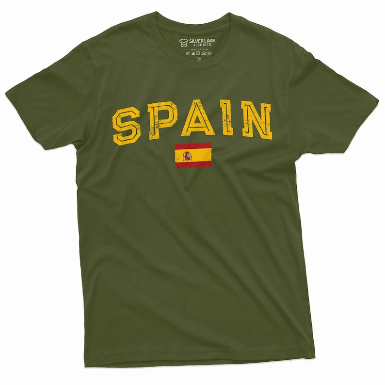 K&ouml;nnte beinhalten: Ein gr&uuml;nes T-Shirt mit dem Wort "SPAIN" in gelben Buchstaben mit einem abgenutzten Look. Die spanische Flagge ist unter dem Wort gedruckt.