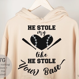 May include: A beige hoodie with a black graphic design that says "HE STOLE my like HE STOLE Your Base" with a baseball and bats. The text "SVG File for cutting machines + PNG file included!" is in the lower left corner.