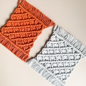 Peut inclure: Deux dessous-de-verre en macram&eacute; faits &agrave; la main, l'un de couleur orange br&ucirc;l&eacute;e et l'autre de couleur gris clair. Les deux dessous-de-verre pr&eacute;sentent un motif en losange et une bordure en franges.