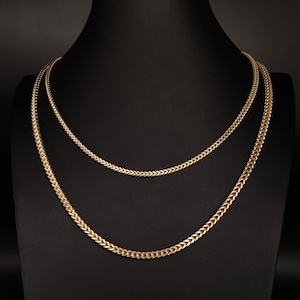May include: Two gold chain necklaces on a black display stand. The chains are both the same style, but one is thicker than the other.