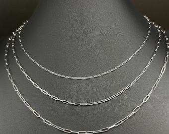 Può includere: Tre collane d'argento esposte su un manichino nero. Le collane sono di diverse lunghezze e presentano delicate maglie a catena. Le catene sono realizzate in un materiale metallico lucido e sono disposte a strati.