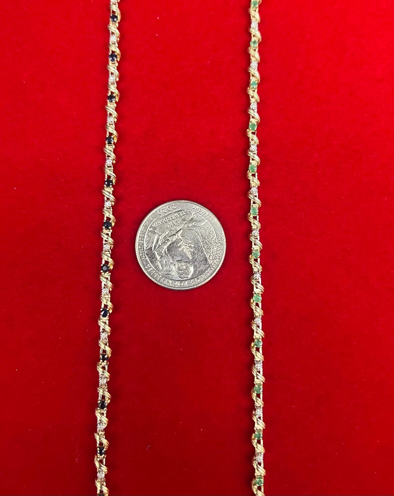 May include: Two gold chains with alternating black and green gemstones. The chains are on a red background. A US quarter is included for size reference.