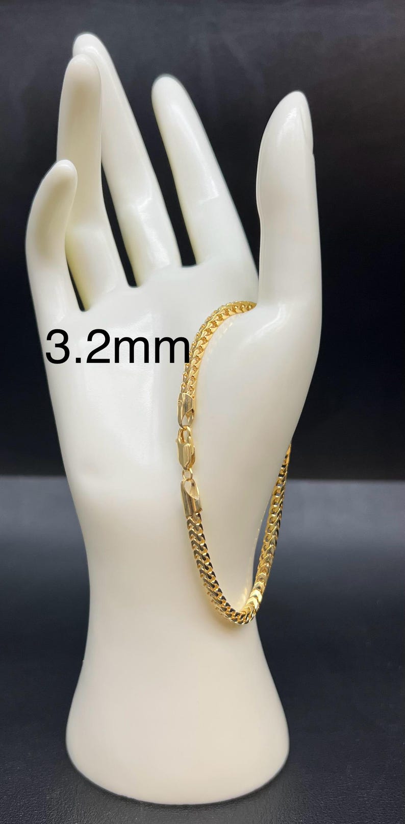 May include: A gold chain bracelet with a 3.2mm width. The bracelet is on a white mannequin hand.