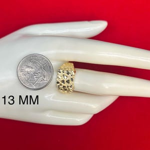 May include: A gold ring with a textured surface. The ring is 13 mm wide. The ring is displayed on a white hand model.