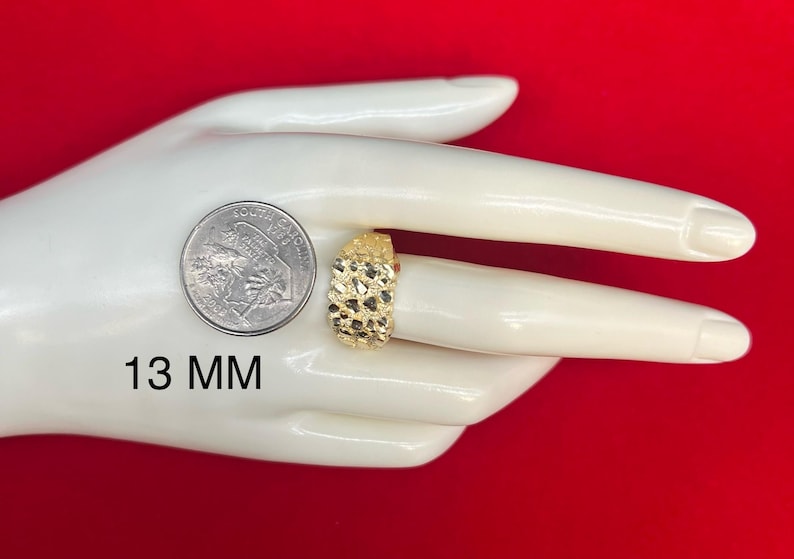 May include: A gold ring with a textured surface. The ring is 13 mm wide. The ring is displayed on a white hand model.