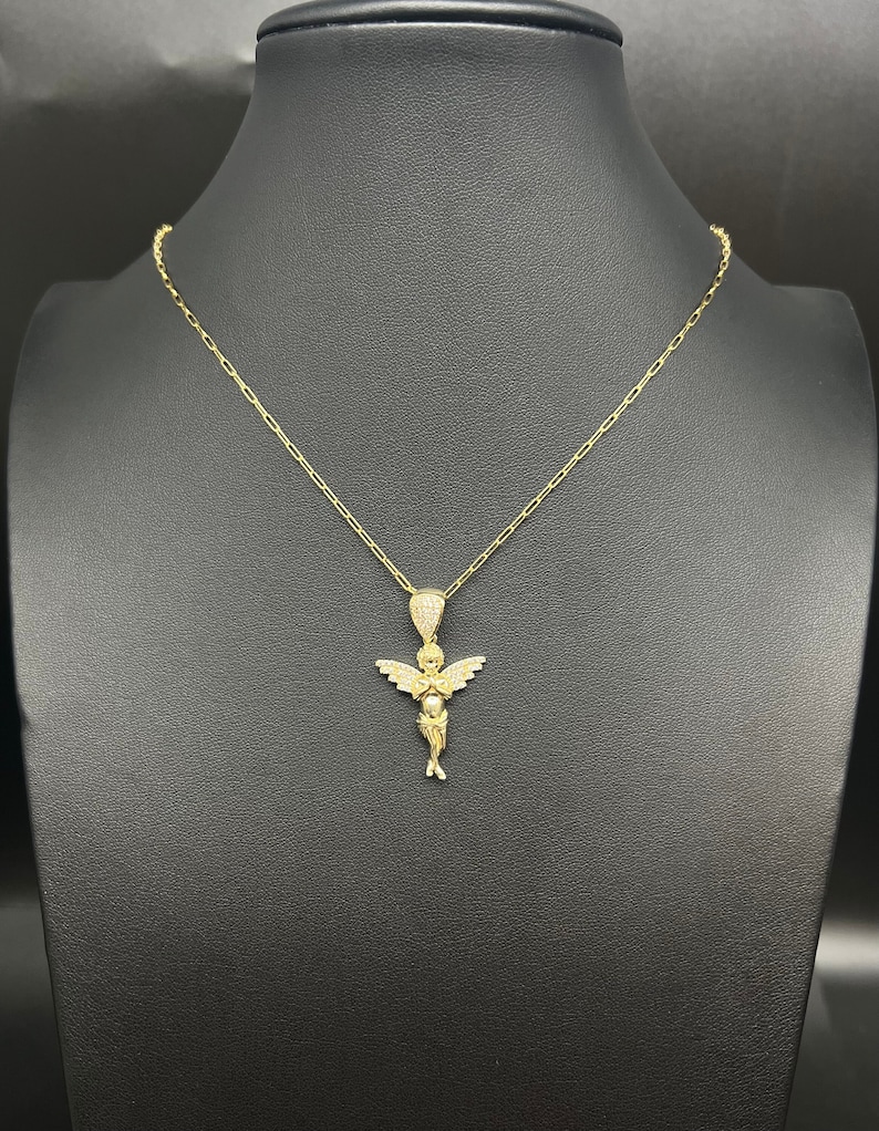 #GoldAngelNecklace
#14KGoldCharm
#AngelicJewelry
#PaperclipsChainNecklace
#ZirconiaStoneCharm
#HeavenlyDesign
#RealGoldPendant
#DivineElegance
#ChicGoldAccessories
#AngelicCharm
#LuxuryGoldNecklace
#PendantAndChain
#CulturalCraftsmanship