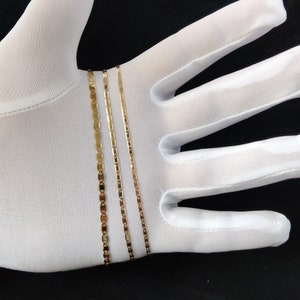 May include: Four gold chains of different widths and styles, displayed on a white surface.