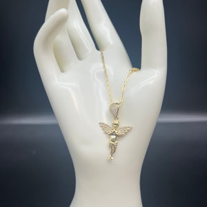Puede incluir: Un collar de cadena de oro con un peque&ntilde;o colgante de &aacute;ngel detallado. El &aacute;ngel est&aacute; adornado con piedras de circonita c&uacute;bica transparentes.